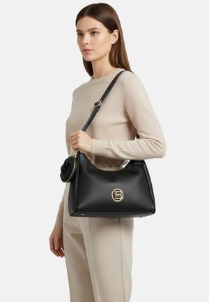 Borsa a mano in pelle nera con logo rotondo dorato, decorazione a fiore rimovibile e tracolla lunga. Design strutturato, texture liscia, interno spazioso.