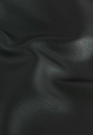 Juodas tekstūruotas oda su lygiu paviršiumi, turinti subtilių raukšlių ir atspindinčių savybių, rodančių minkštumą ir lankstumą.