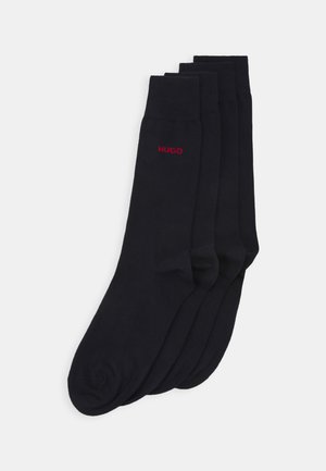 Schwarze Baumwollsocken mit gerippten Bündchen, ausgestattet mit einem kleinen roten "HUGO"-Logo. Jede Socke hat eine glatte, leicht dehnbare Textur.