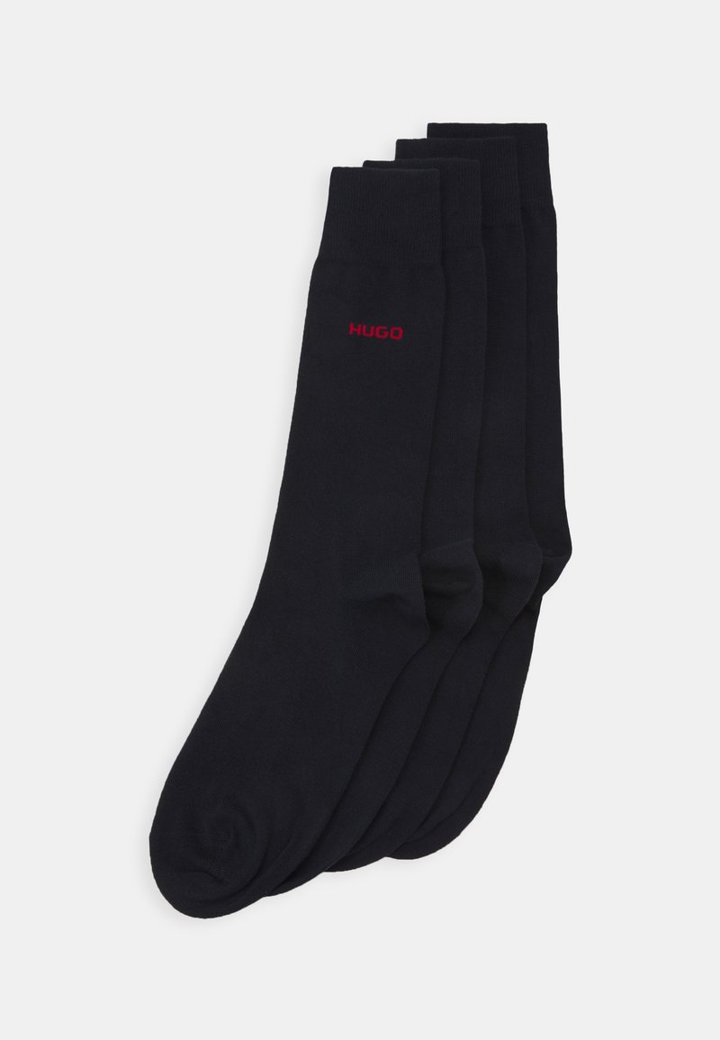 Schwarze Baumwollsocken mit gerippten Bündchen, ausgestattet mit einem kleinen roten "HUGO"-Logo. Jede Socke hat eine glatte, leicht dehnbare Textur.