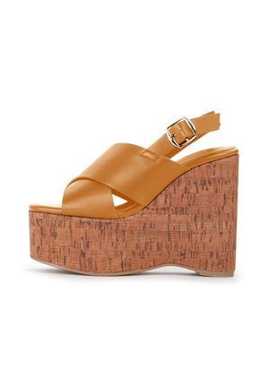 Sandali platform beige con tacco in sughero. Presentano cinghie incrociate opache e una fibbia regolabile alla caviglia. Texture della superficie liscia.