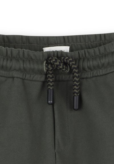 Olijf groene joggers met een elastische tailleband, voorzien van een gevlochten strik en zwarte plastic aglets. Zachte textuur en minimale stikdetails zichtbaar.