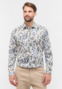 Wit overhemd met lange mouwen, versierd met een kleurrijk paisley- en bloemenpatroon met groene, blauwe, bruine en gele accenten. Klassiek kraagontwerp.