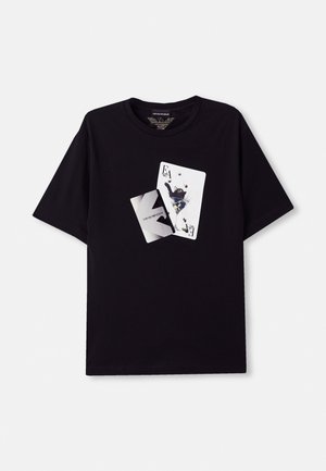 T-shirt en coton noir avec un imprimé graphique de cartes à jouer et une illustration sur le devant, col rond et manches courtes.