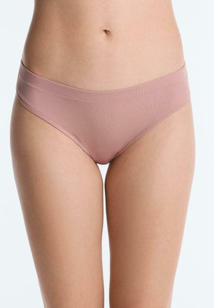 Parte inferiore del torso di una donna che indossa biancheria intima a bikini rosa chiaro a coste, su sfondo bianco uniforme.