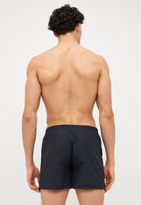 Shorts de bain noirs avec une ceinture élastique, tissu léger et un design simple et épuré. Pas de motifs ou d'accents visibles.