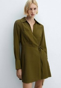 Olive green wrap dress with a collar, long sleeves, and a tie at the waist. Features a front pocket and a smooth, lightweight texture.