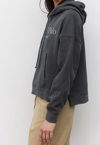 Grijze cropped hoodie van zachte stof, met een voorzak, capuchon met trekkoord en geborduurd logo op de borst.