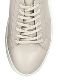 Beżowe skórzane trampki z okrągłym noskiem, teksturowanym wierzchem, płaskimi sznurowadłami i kontrastującą białą gumową podeszwą. Posiadają subtelne detale przeszycia.