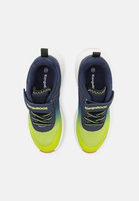 Marineblauwe en limoen groene sportschoenen van mesh stof, met witte zolen en zwarte veters. Ze hebben decoratieve stiksels en een klittenbandsluiting.