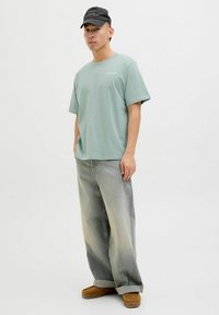 Lys grøn bomulds t-shirt, afslappet pasform, rund hals. Matchet med lysegrå denim jeans og brune ruskindssko. Sort kasket fuldender looket.