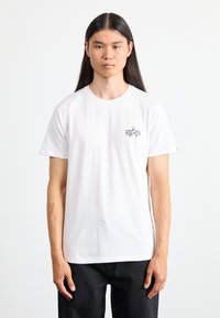 Weißes Baumwoll-T-Shirt mit Rundhalsausschnitt, versehen mit einem kleinen schwarzen Stern-Logo auf der linken Brust und kurzen Ärmeln; klassischer gerader Schnitt.