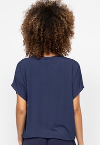 Marineblauwe T-shirt met korte mouwen, een ontspannen pasvorm, een gladde textuur en omgeslagen mouwen. De achterzijde toont eenvoud en een gelijkmatige snit.