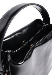Bolso de cuero negro brillante con asa corta, parte superior abierta que muestra un bolsillo interior con dos botones de presión metálicos.