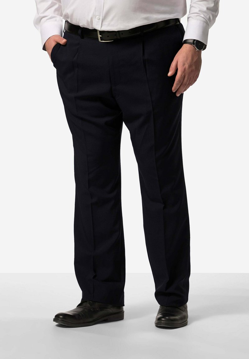 Marineblaue, plissierte Anzughose in maßgeschneiderter Passform, hergestellt aus glattem Stoff. Abgerundet mit einem Ledergürtel und schwarzen Dressschuhen.