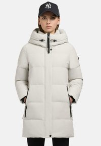 Piumino bianco con cappuccio, dotato di chiusura con zip, tasche laterali e dettagli neri. Texture liscia e motivo trapuntato su tutta la superficie.