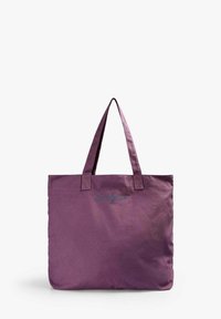 Bolsa de lona púrpura con dos asas resistentes y una sutil marca en azul. Diseño simple, interior espacioso y textura duradera.