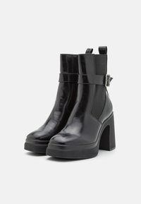 Schwarze Leder Stiefeletten mit glänzender Oberfläche, elastischen Seiteneinsätzen, einer Schnallendekoration und einem stabilen hohen Blockabsatz. Flache Gummisohle für Stabilität.