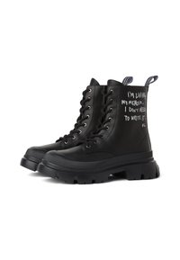 Čierne kožené členkové topánky s hrubou podrážkou, s bielym textom na vonkajších stranách a šnurovacím dizajnom. Text znie: "Žijem svojom memoároch..."