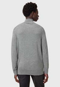 Maglione grigio con alto collo, maniche lunghe e orlo a coste. Realizzato in un tessuto morbido, presenta sottili dettagli di cucitura.