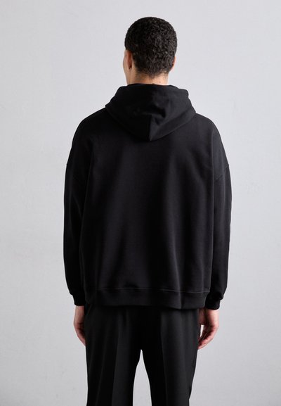 Črna kapuca s sweatshirtom, narejena iz mehke tkanine, z relaxed fit krojem, spuščeni rameni ter rebrastimi manšetami in obrobami za udobje.