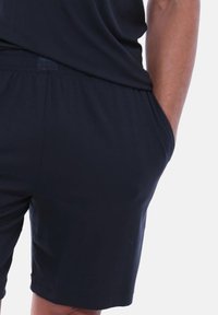 Pantaloncini blu navy con vestibilità comoda, dotati di cintura elastica e tasche laterali. Tessuto liscio senza motivi o decorazioni visibili.