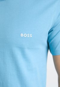 Lyseblå kortermet t-skjorte laget av glatt bomull, med en liten hvit brodert "BOSS"-logo på forsiden.