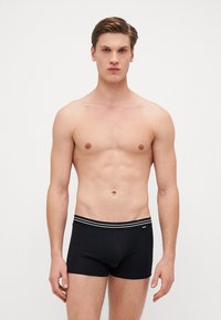 Schwarze Boxer-Brief aus Baumwolle mit enganliegender Passform, ausgestattet mit einem gestreiften elastischen Bund und einer glatten Oberfläche.