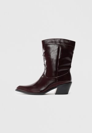 Bottines en cuir bourgogne avec un bout pointu, une surface texturée et un petit talon effilé. Présente une couture discrète et un ajustement confortable.