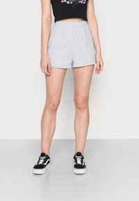 Gray cotton shorts with an elastic waistband, paired with a black crop top and black sneakers with white accents on a neutral background.