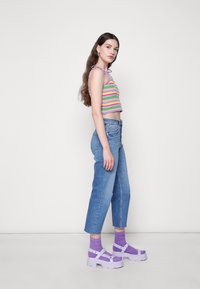 Top de crochê cropped com riscas multicoloridas, jeans de cintura alta azul claro e sapatos de plataforma chunky em lavanda com tiras.