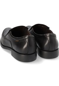 Zapatos de piel negra tipo slip-on con un acabado liso, punta redondeada y costuras mínimas. Cuentan con una suela de perfil bajo para mayor comodidad.