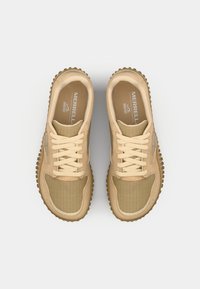 Beige athletic shoes featuring a textured upper, round laces, and a flexible rubber sole with a patterned tread design.