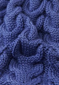 Close-up of textured blue knitted fabric with raised cable stitch pattern and visible soft yarn fibers.