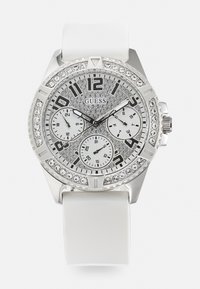 Orologio argento con cinturino in gomma bianca, lunetta di cristallo scintillante e quadrante argentato testurizzato che presenta grandi numeri e tre sottoquadranti.