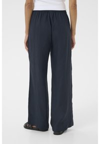 Schlichte navyblaue weit geschnittene Hosen aus leichtem Stoff, mit einem elastischen Bund und einer glatten Textur, die eine lockere Passform zeigen.