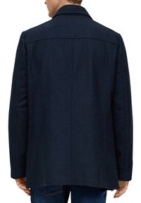 Marineblauwe wollen jas met visgraattextuur, klassieke reverskraag en rechte snit, met een rugstuk en zijzakken.