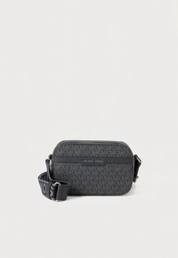 Siva monogram torbica preko ramena s teksturiranim završetkom, zatvaračem na patentni zatvarač i podesivim remenom s logotipom brenda.