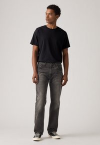 Black t-shirt, gray jeans, and black-and-white patterned sneakers. Jeans have a straight cut, and shirt has a crew neck design.