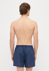 Ναυτικά μαγιό καρό με ελαστική μέση, κατασκευασμένα από ελαφρύ ύφασμα. Σχεδιασμένα για άνεση και γρήγορο στέγνωμα.