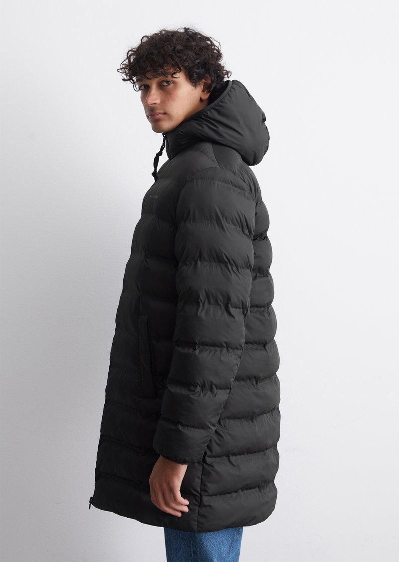 Schwarze gepolsterte Daunenjacke mit Kapuze, ausgestattet mit einem Reißverschluss, zwei Seitentaschen und einem gesteppten Design. Modell von der Seite gezeigt.
