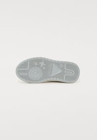 Grå gummisko sål med et fiskebensmønster. Har branding og cirkulære detaljer, glat tekstur og afrundet tåform.