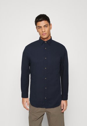 Camicia a maniche lunghe blu navy, in tessuto di cotone, colletto con bottoni, vestibilità dritta, design minimalista, senza modelli o accenti visibili.