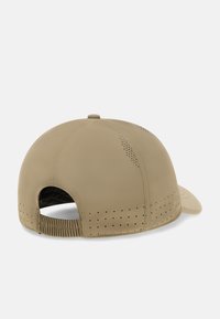 Gorra beige con visera curva, hecha de material suave. Presenta agujeros de ventilación perforados, correa trasera flexible y diseño de corona redondeada.