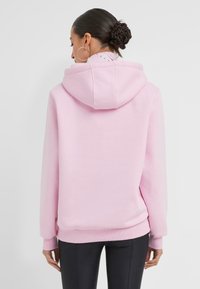 Sweat-shirt à capuche rose avec une coupe décontractée, des poignets et un ourlet côtelés. Matériau doux avec une texture lisse et un design simple.