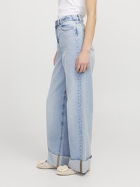Light blue, wide-leg jeans with a high waist and frayed hems. Features classic denim texture and subtle fading. Paired with woven shoes.