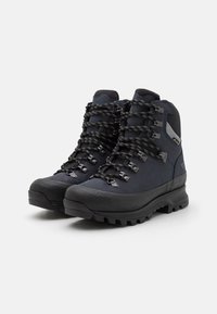 Høyde hiking-støvler i mørk blå med svarte detaljer, laget av slitesterke materialer, metallhull, strukturert gummisåle og mønstrede snørebånd.