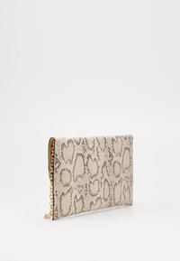 Beige laukku, jossa on käärmeennahkakuosi ja osittain näkyvä kultaketjuhihna yksinkertaista valkoista taustaa vasten.