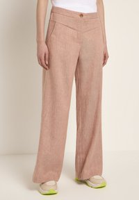 Light pink, wide-leg trousers with a textured appearance, featuring a high waist, button closure, and diagonal front pockets.