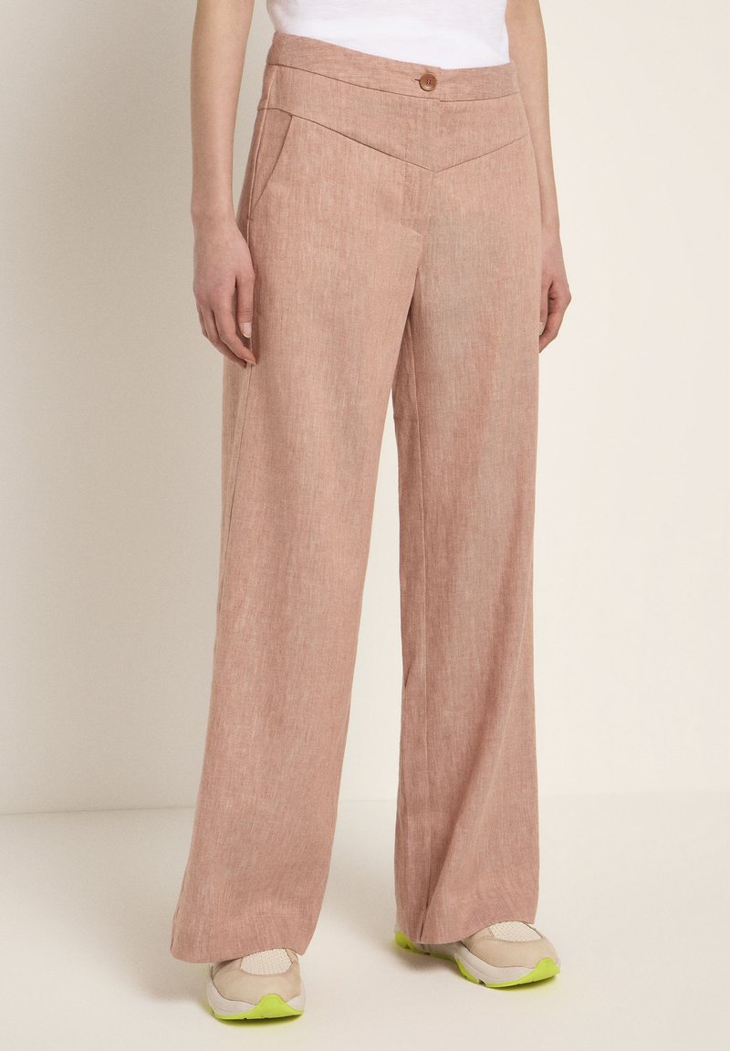 Light pink, wide-leg trousers with a textured appearance, featuring a high waist, button closure, and diagonal front pockets.